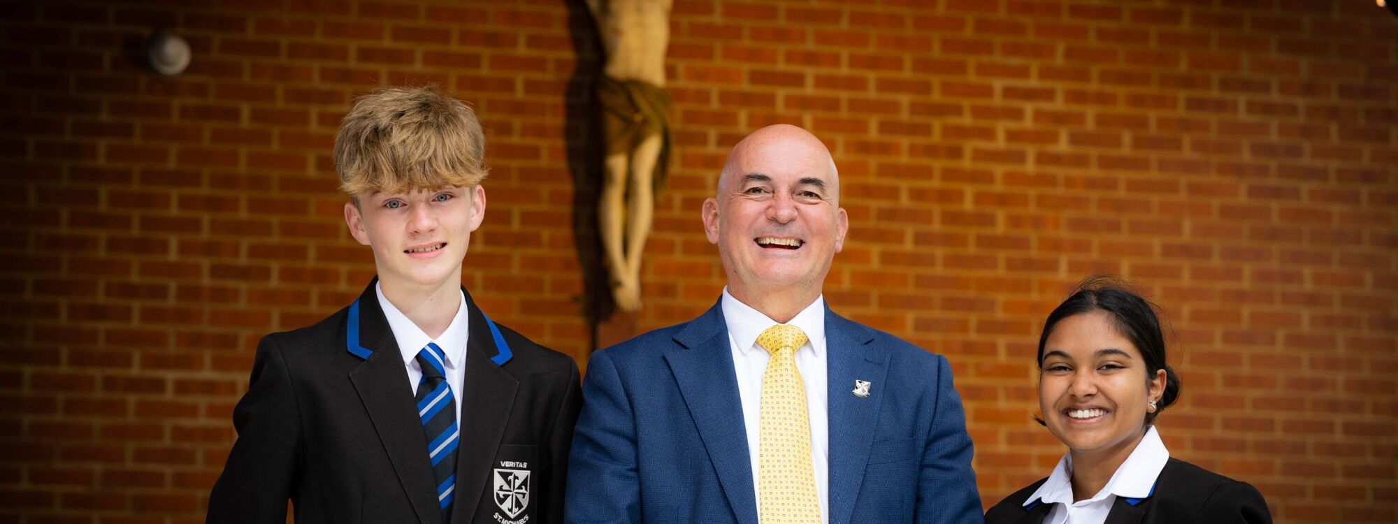 St M's Headteacher and students in front of crucifix 2024